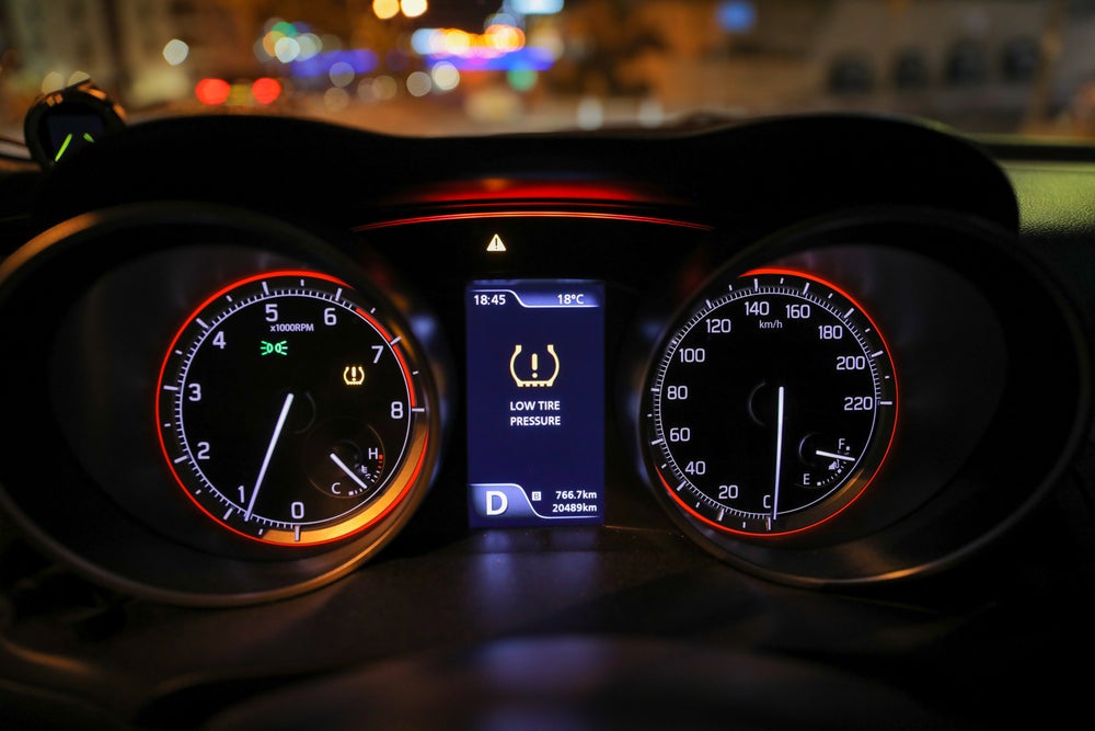 Vehicle dashboard displaying a low tire pressure warning alert.